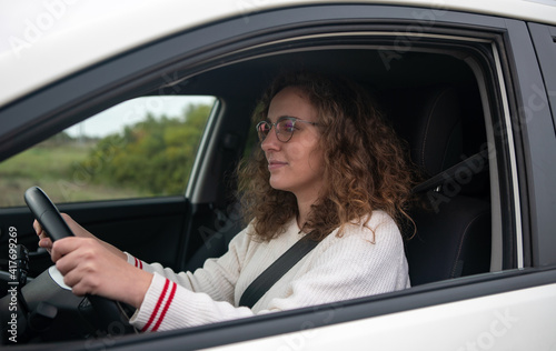 Young woman driving a car, concept of new driver. Woman has curly blonde hair.
