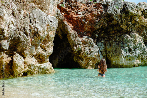 beautiful woman in swimsuit in sea water near grotto