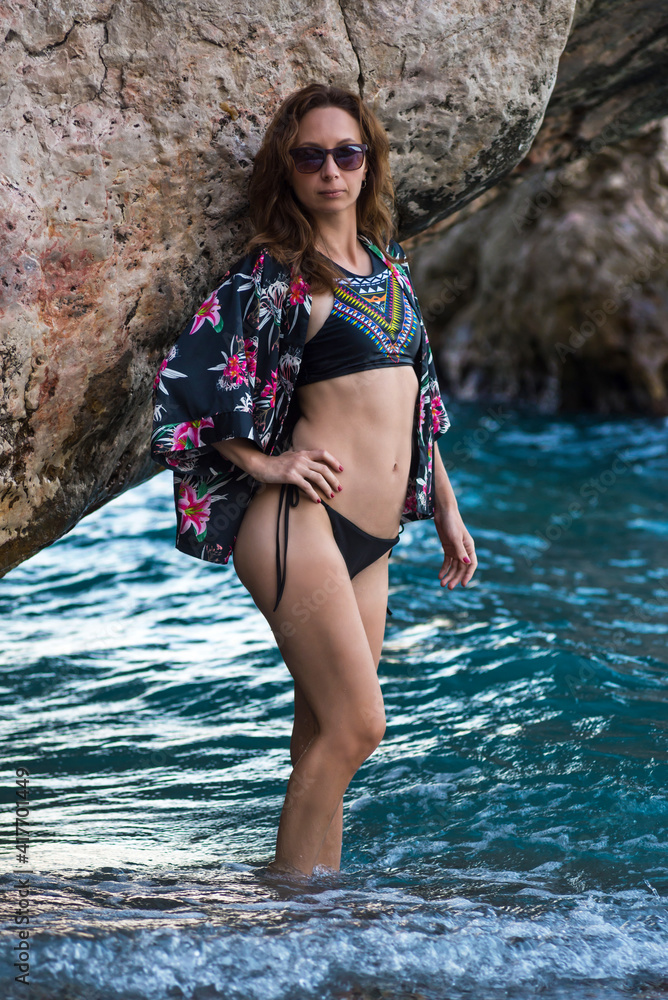Young woman posing in a swimsuit at the sea near the cliff. Young woman posing in a swimsuit at the sea near the cliff.