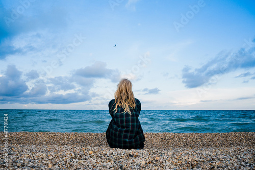The girl sits on the seashore and looks into the distance