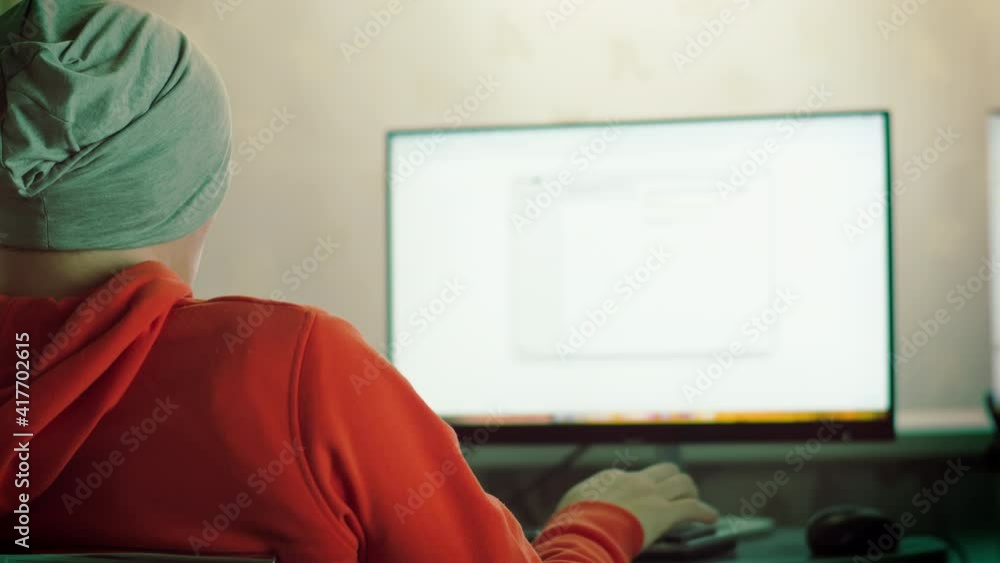 A man in a gray hat works while sitting at a laptop, remote work A man in a gray hat works while sitting at a laptop, remote work