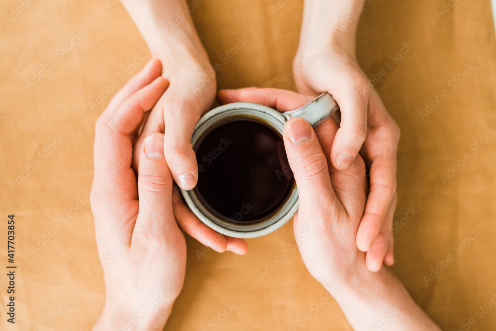 Woman's and men's hands holding hot cup of tea Woman's and men's hands holding hot cup of tea
