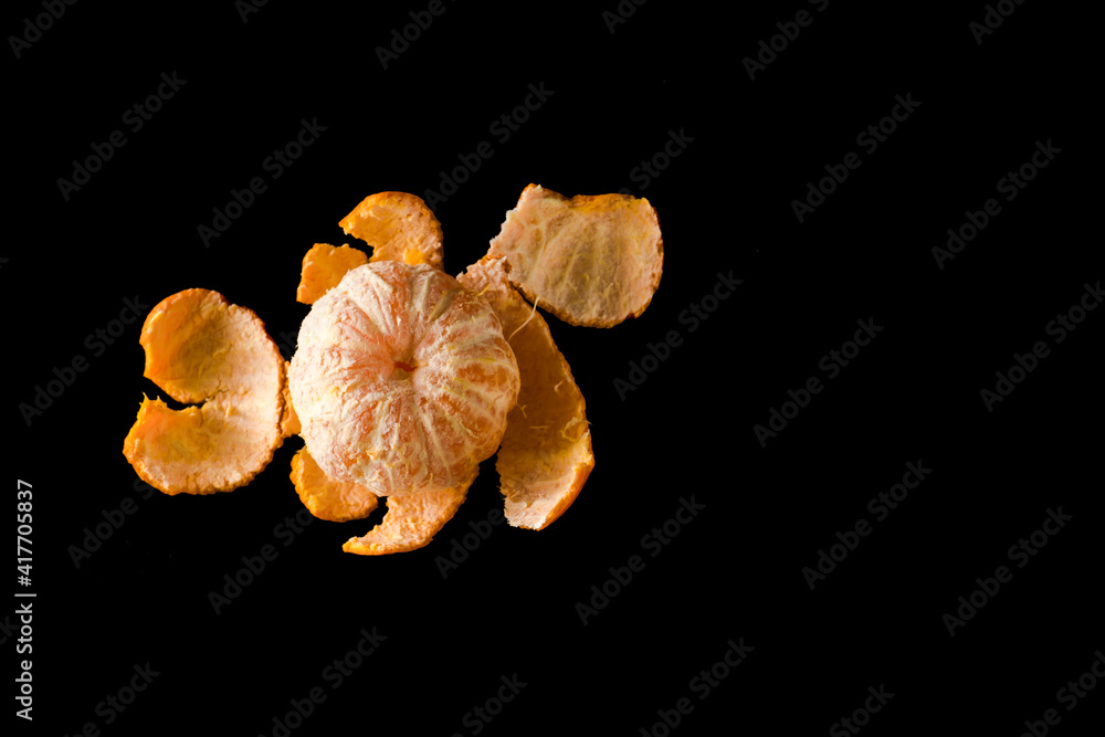 Ripe citrus fruit of the mandarin plant, peeled from the peel, on a black background Ripe citrus fruit of the mandarin plant, peeled from the peel, on a black background