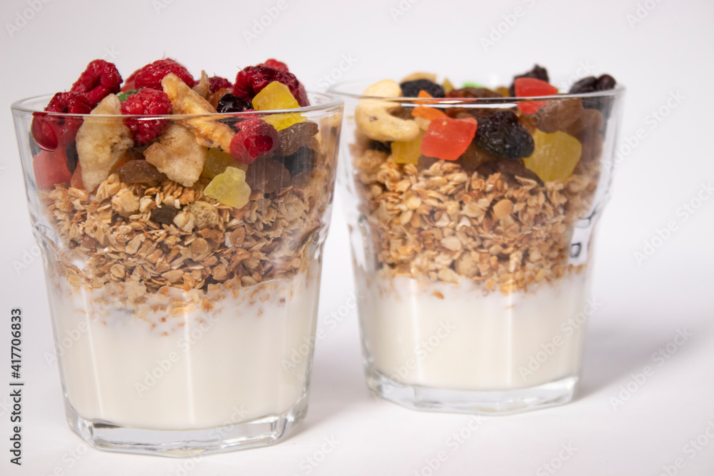 muesli dessert with yogurt and candied or dried fruits with raspberries on top in glass isolated on white background. Granola breakfast muesli dessert with yogurt and candied or dried fruits with raspberries on top in glass isolated on white background. Granola breakfast