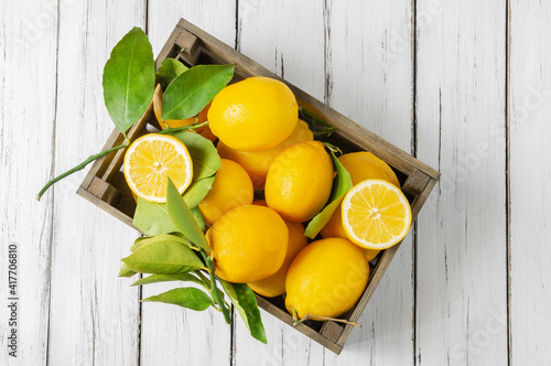 Fresh ripe yellow lemon fruits with leaves on white wooden background