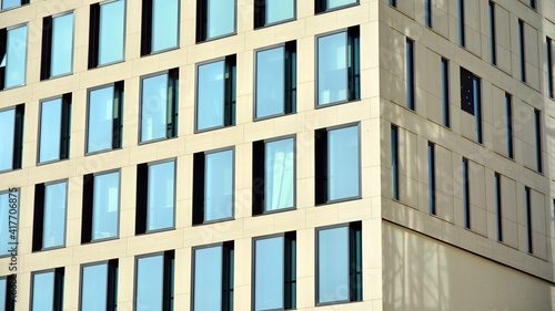 A fragment of the glass and sandstone facade of a modern office building. Wide abstract fragment of modern building facade. View of modern glass and stone facade.