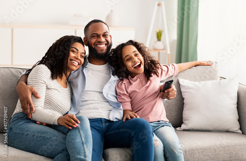 Happy young family watching television sitting on sofa photo