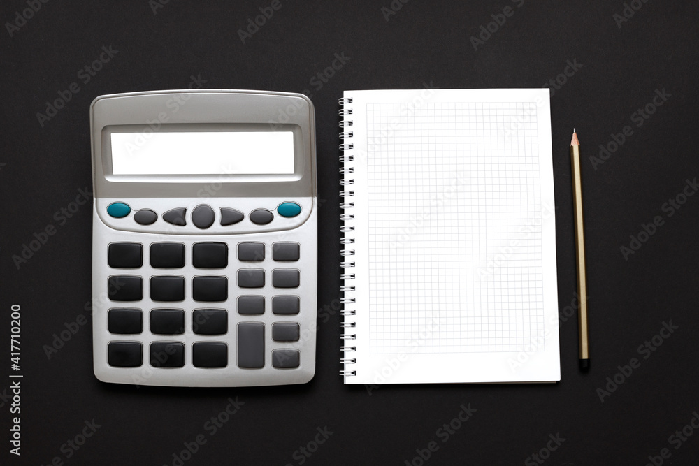 calculator, white paper notebook and pencil on a black background calculator, white paper notebook and pencil on a black background
