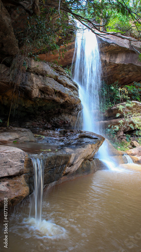 A vertical shot of a small waterfall during the dayti photo