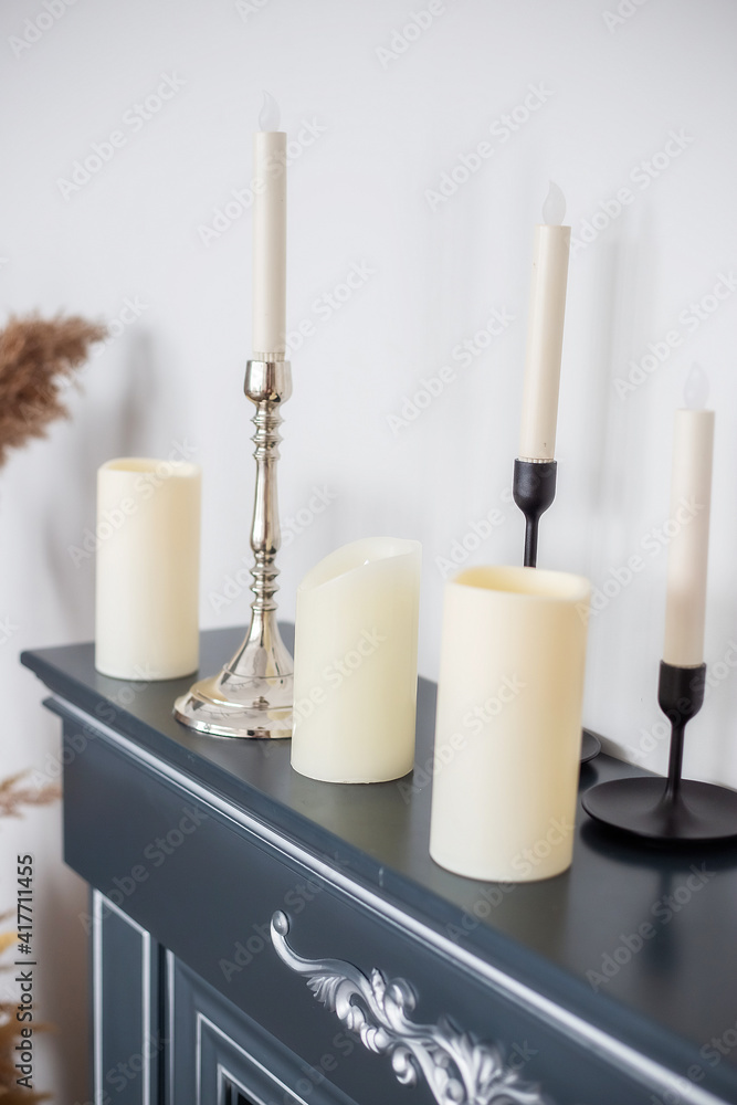 Fototapeta premium Candles of various types and sizes with and without candlesticks on fireplace