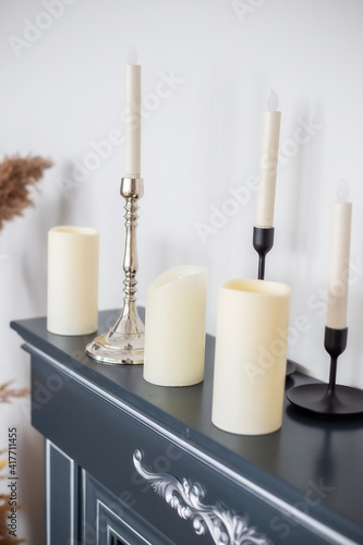 Candles of various types and sizes with and without candlesticks on fireplace