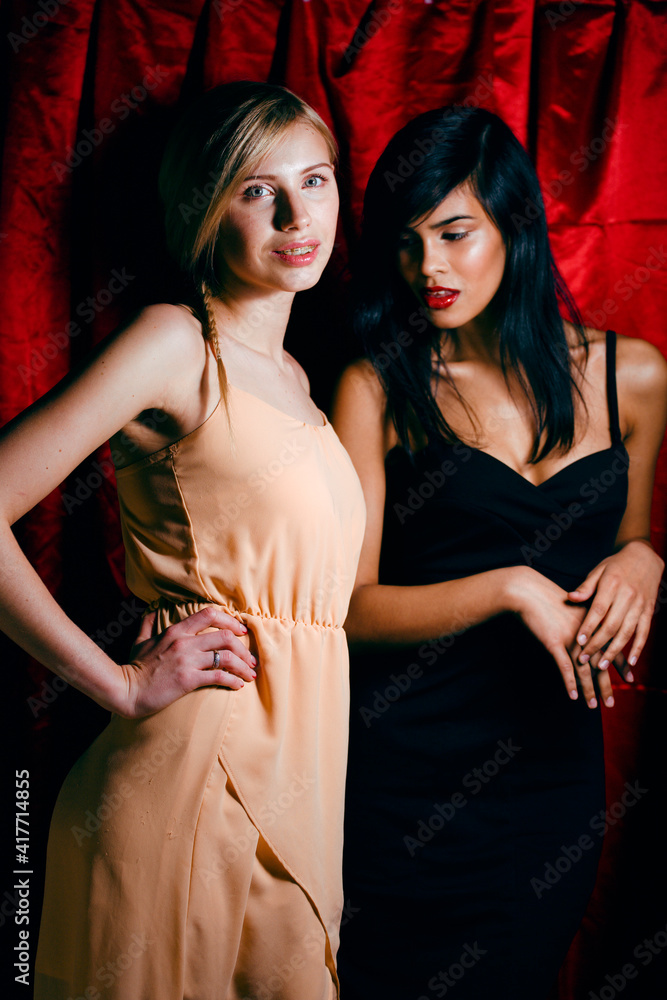 brunette and blond woman together friends on red background, conflict of types brunette and blond woman together friends on red background, conflict of types