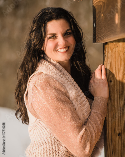 woman leaning against hay bales in snow
