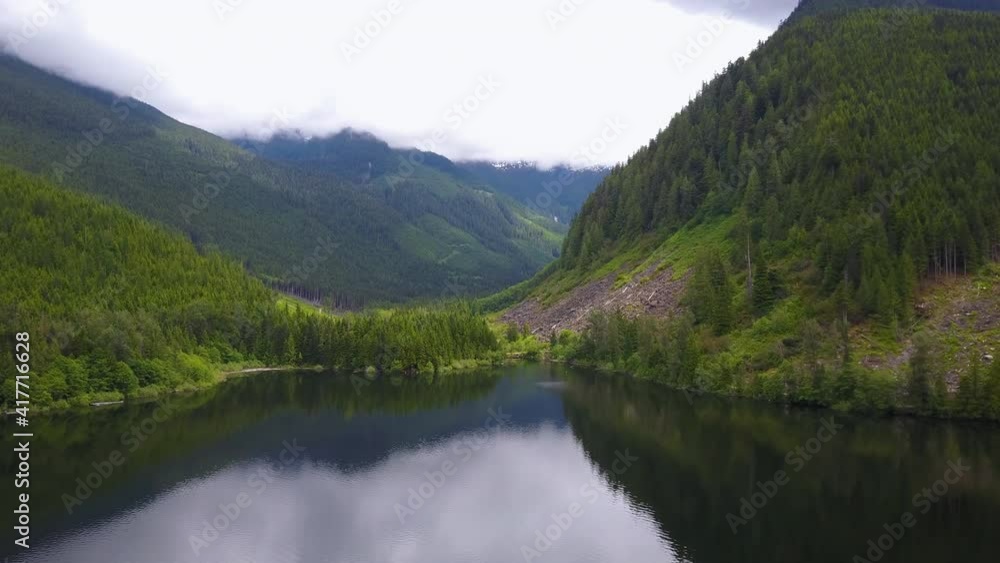 A small lake, huge hills covered by various plants, and majestic mountains in the distance. Mountains in harmony with the river and hills A small lake, huge hills covered by various plants, and majestic mountains in the distance. Mountains in harmony with the river and hills
