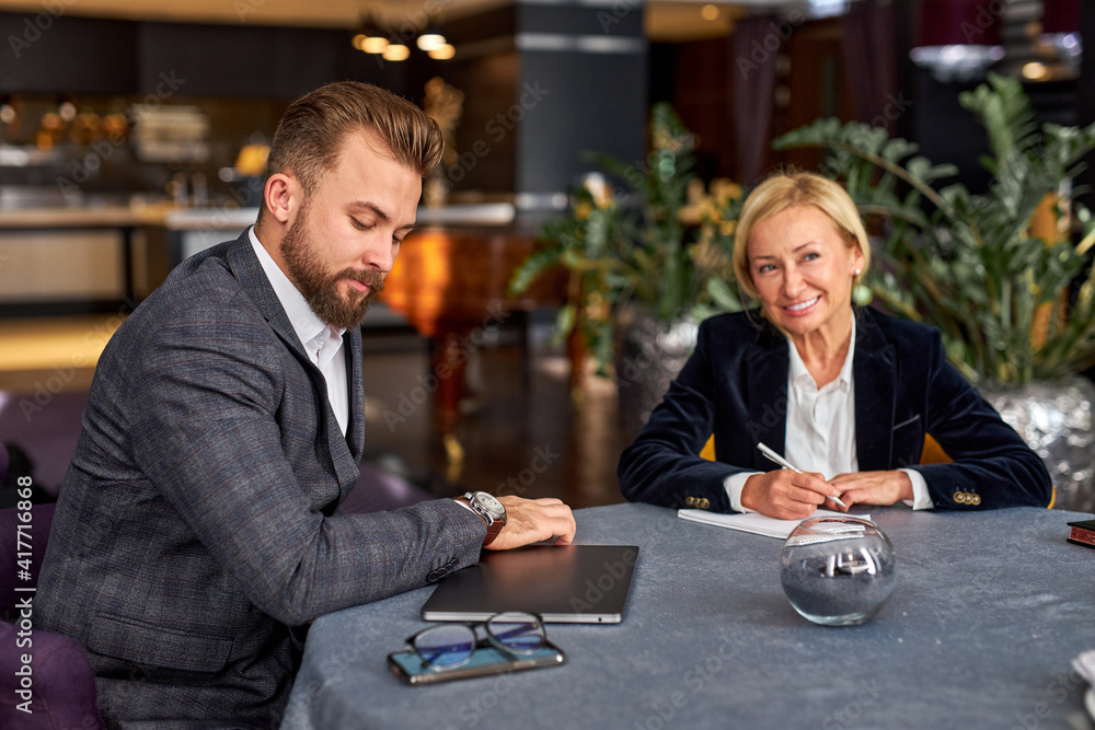 female translator writes down all the business strategies coming out of the mouth of a smart confident businessman, in restaurant female translator writes down all the business strategies coming out of the mouth of a smart confident businessman, in restaurant