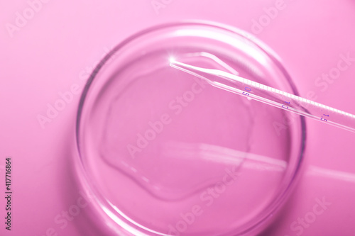 Pipette drops the sample into a test tube against a pink background. Medical abstract background. Cosmetic concept