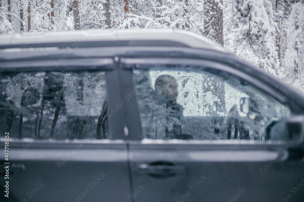 Obraz premium man follows the road in a navigator and drives a car through a winter forest