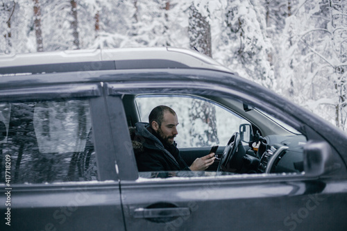 man follows the road in a navigator and drives a car through a winter forest