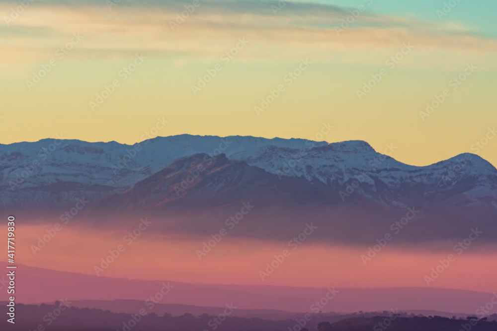 Mountains landscape with snowy peaks and colorful by the sunrise sun.