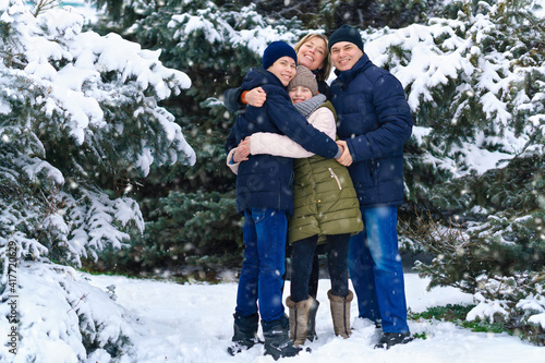 family portrait in the winter forest, parent and children, beautiful nature with bright snowy fir trees © soleg