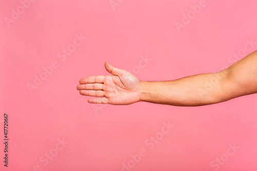 Caucasian man hand hanging something blank isolated on a pink background. Close-up.