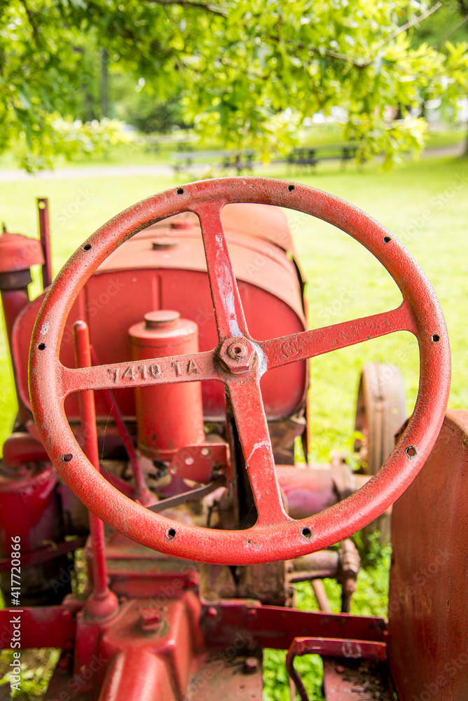 A red steering wheel on an old tractor. 