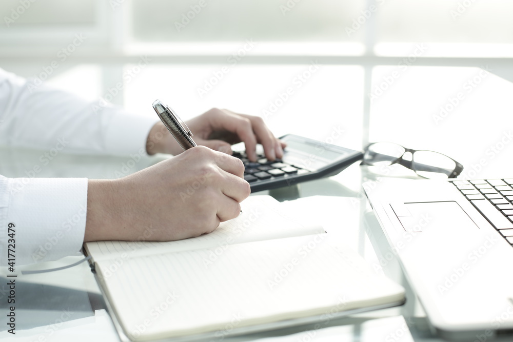 The manager works in the office, keeps notes in a notebook and counts on a calculator The manager works in the office, keeps notes in a notebook and counts on a calculator
