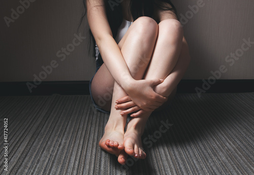 Battered young woman sitting near wall