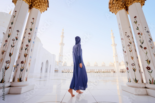 Traveling by Unated Arabic Emirates. Woman in traditional abaya standing in the Sheikh Zayed Grand Mosque, famous Abu Dhabi sightseeing. photo