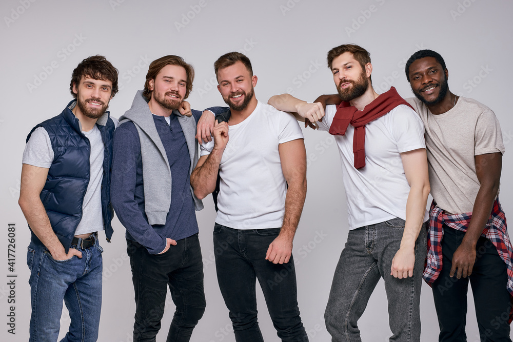 © Roman - cheerful diverse men in casual urban style clothes posing at camera, stand together having talk and cmile, laugh. isolated white background