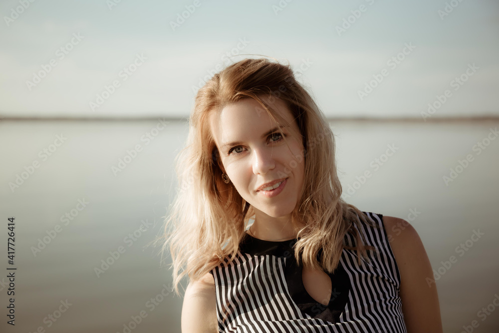 A young charming girl with hidden skin, happy eyes and a gentle smile looks into the distance while being outdoors during evening sunset. The happy face of a person in anticipation of good news. A young charming girl with hidden skin, happy eyes and a gentle smile looks into the distance while being outdoors during evening sunset. The happy face of a person in anticipation of good news.