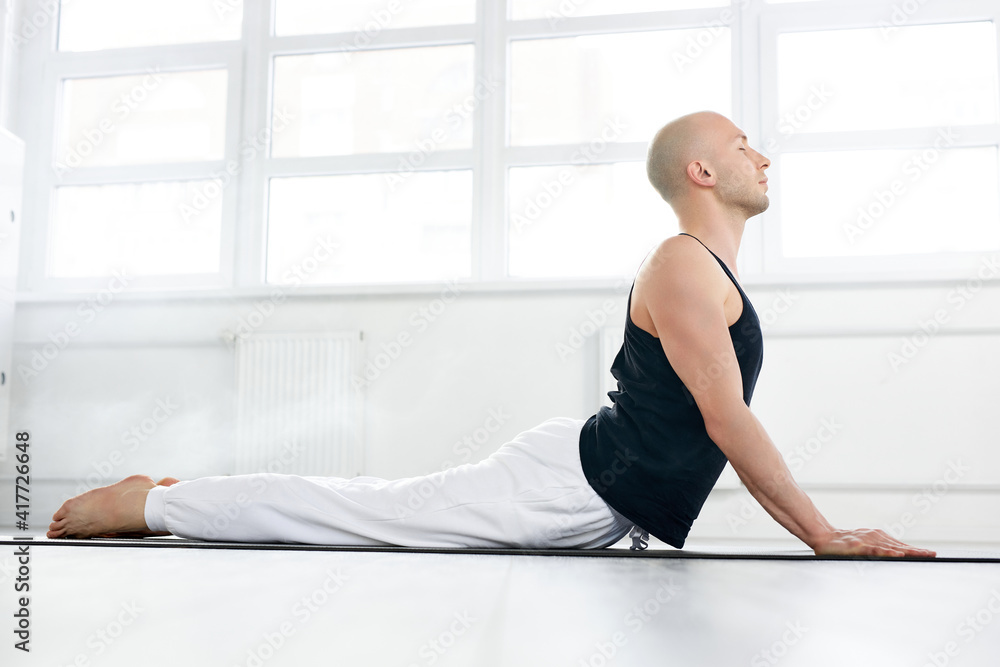 Fototapeta premium yogi man doing yoga exercise isolated on white background indoors. Yogi master workout alone, concentrated on stretching. Yoga lifestyle healthy, sport concept.