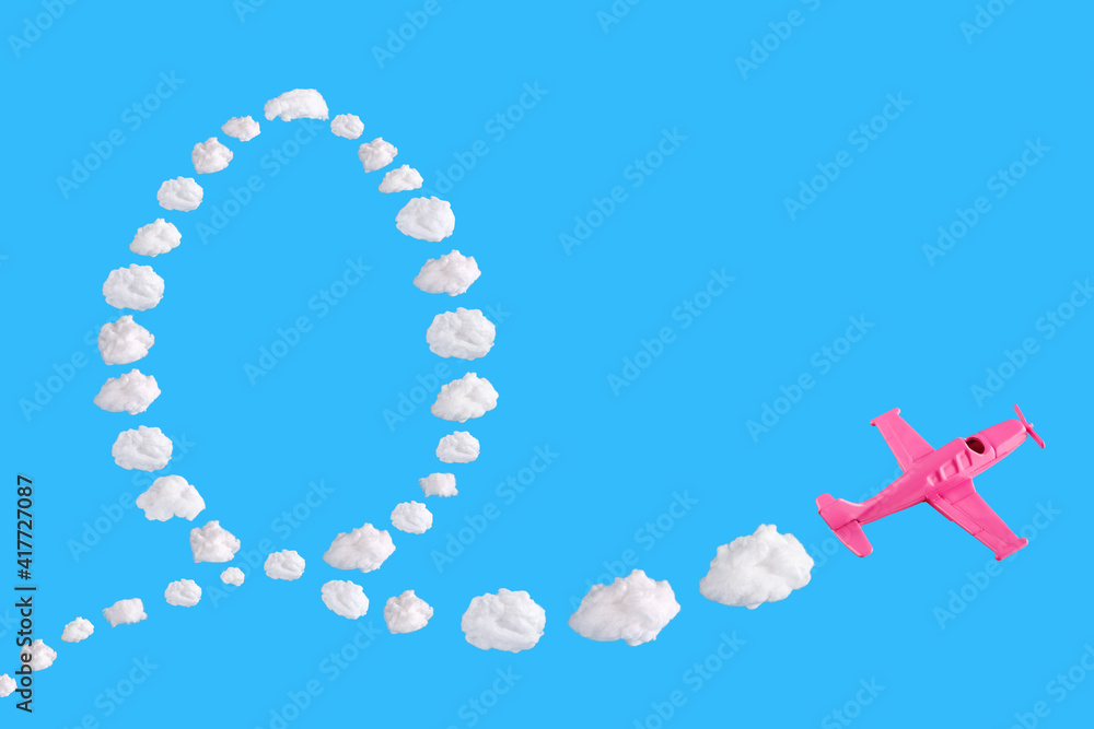 Naklejka premium Pink airplane goes into a sharp turn on blue background and easter egg of abstract shapes of cloud. Festive minimal composition. Happy easter holiday concept, copy space 