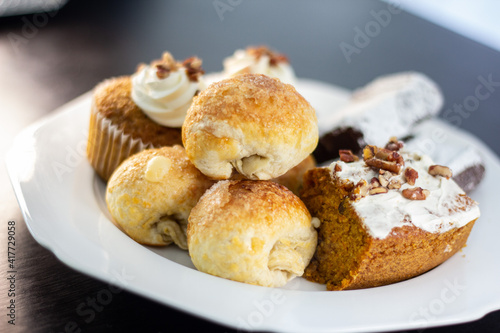 panes horneados en plato blanco con fondo negro, bola de queso, panqué de nuez, brownie, cupcake