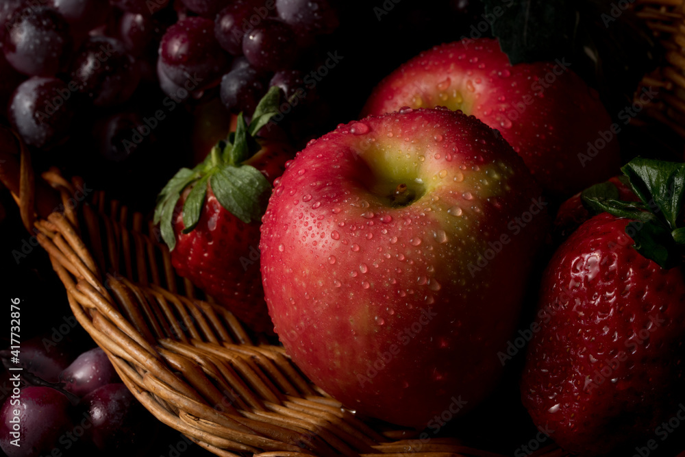 Fruit basket still life with fresh fruits in a wicker basket on black background with copy space Fruit basket still life with fresh fruits in a wicker basket on black background with copy space