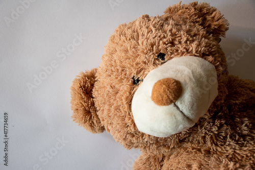 Cute teddy bear with a smile over a white background, nice toy for a happy child. Located on the right side.