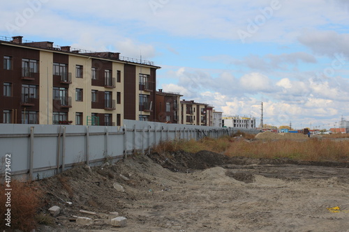a dirty wasteland behind a fence near high-rise buildings in a ghetto on the outskirts of the city depressive