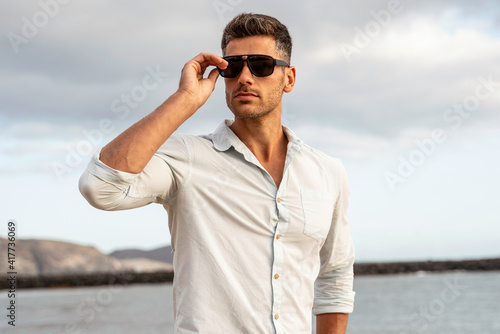 Gorgeous stylish man wearing fashionable shirt and sunglasses. City style.
