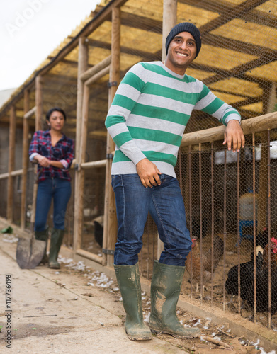 Smiling male proffesional farmer standing at chicken house at farm