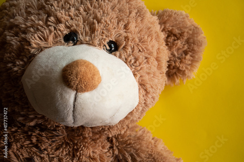 Happy and cute teddy bear with a smile over a yellow background  toy for a happy child. Close up view. © Manu Arteaga