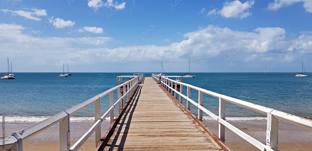 Wooden white bridge to the sea with dramatic sky view over the long jetty in Hervey Bay Australia