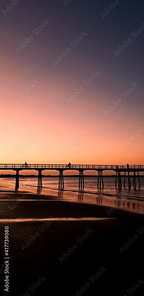 two people riding a bicycle on the jetty,  beautiful sunset with a jetty at Hervey Bay, Queensland, Australia, 