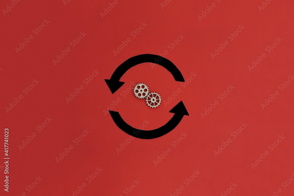 Two round black arrows, two wooden gears on a red background. Action, movement. Two round black arrows, two wooden gears on a red background. Action, movement.