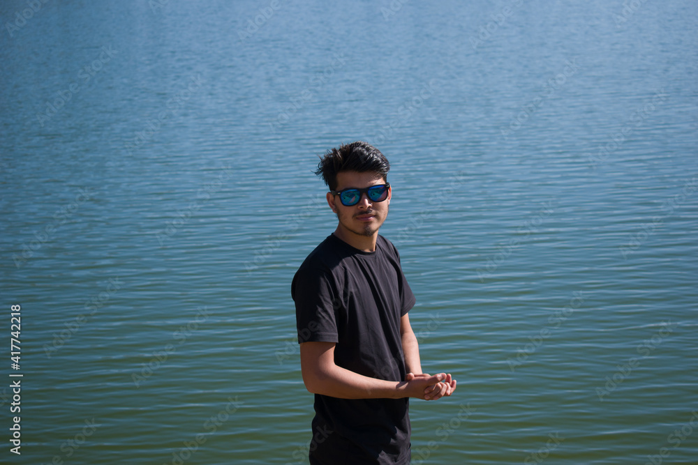indian boy in front of lake and smiling while hands folded