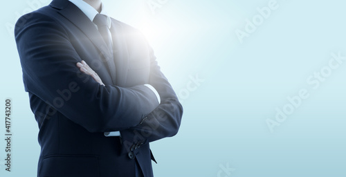 Confident business manager with crossed arms. Pale blue background with backlit. photo