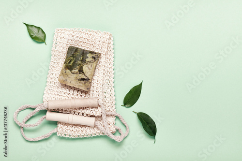 Eco friendly natural hygiene concept. Diy herbal soap and sisal washcloth on green background, copy space photo