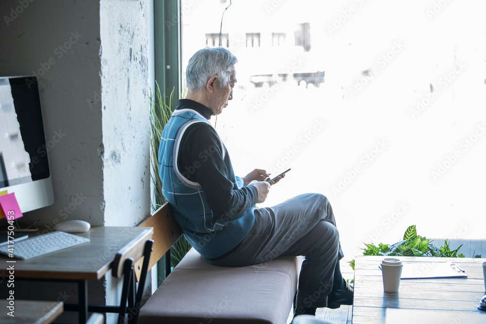 カフェでスマートフォンの操作をしている高齢男性 カフェでスマートフォンの操作をしている高齢男性