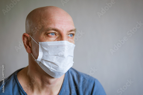emotional portrait of a bald man in a protective mask in a blue t-shirt