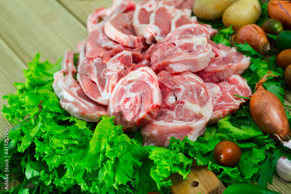 Raw lamb and vegetables assortment on natural wooden desk, cooking ingredients