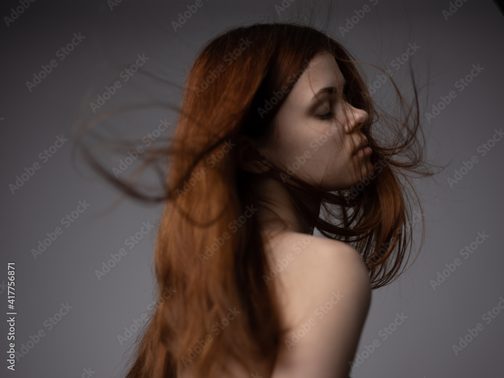 Pretty woman with red hair on a gray background naked shoulders bottom view Pretty woman with red hair on a gray background naked shoulders bottom view